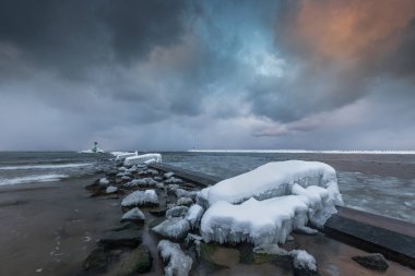 Gorki Zachodnie, Gdansk, Polonya 'daki Baltık Denizi' nde buzla kaplı kayalar ve dalgakıranlar. Deniz feneriyle kışın deniz manzarası.