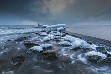 Gorki Zachodnie, Gdansk, Polonya 'daki Baltık Denizi' nde buzla kaplı kayalar ve dalgakıranlar. Deniz feneriyle kışın deniz manzarası.