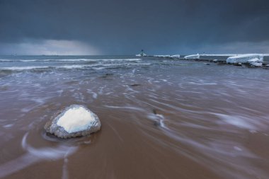 Gorki Zachodnie, Gdansk, Polonya 'daki Baltık Denizi' nde buzla kaplı kayalar ve dalgakıranlar. Deniz feneriyle kışın deniz manzarası.