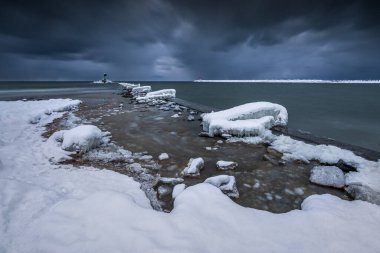Gorki Zachodnie, Gdansk, Polonya 'daki Baltık Denizi' nde buzla kaplı kayalar ve dalgakıranlar. Deniz feneriyle kışın deniz manzarası.