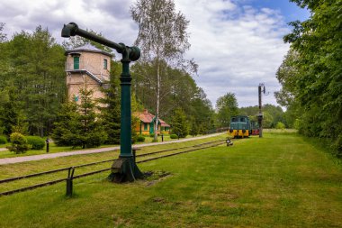 Bialowieza, Polonya - 3 Haziran 2021: Yeşilliklerle çevrili eski tren ve rayların yanındaki tarihi tuğla su kulesi.