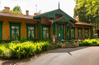 Bialowieza, Polonya - 3 Haziran 2021: Ahşap bina yemyeşil eğrelti otları ve renkli çiçeklerle çevrili.
