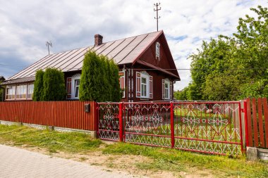 Polonya 'nın Podlasie kentindeki Soce köyünde zengin pencere detayları ve süslü metal çitleri olan geleneksel ahşap ev.