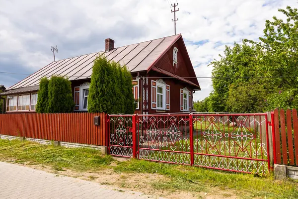 Polonya 'nın Podlasie kentindeki Soce köyünde zengin pencere detayları ve süslü metal çitleri olan geleneksel ahşap ev.