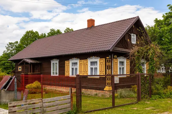 Polonya 'nın Podlasie kentindeki Soce köyünde dekoratif panjurları ve modern çatısı olan ahşap kırsal bir ev..