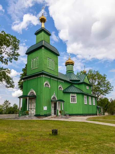 Trzescianka, Polonya 4 Haziran 2021: Podlasie 'de altın kubbeleri olan yeşil Ortodoks ahşap kilisesi yakınlarında yürüyen insanlar.