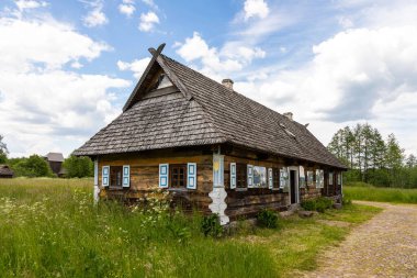 Bialowieza, Polonya 5 Haziran 2021: Mavi pencereli geleneksel ahşap ev ve dışarıda oturan bir ziyaretçi.