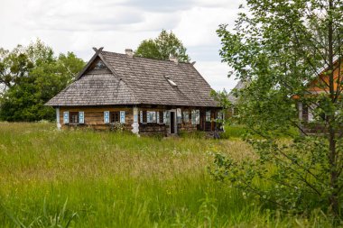 Bialowieza, Polonya 5 Haziran 2021: Mavi pencereli geleneksel ahşap ev ve dışarıda oturan bir ziyaretçi.