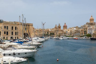 Valletta, Malta - 21 Haziran 2021: Yat ve yelkenliler tarihi şehir binaları ve kilise kubbeleri ile marinada demirlediler.