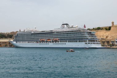 Valletta, Malta 21 Haziran 2021: Limanda demirlemiş bir Viking okyanus yolcu gemisi ve yakınlardan geçen küçük bir tekne.
