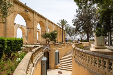 Valletta, Malta 21 Haziran 2021: Limana bakan halka açık bir parkta sıralı ve çiçek açan bahçeli kemerli yürüyüş yolu.