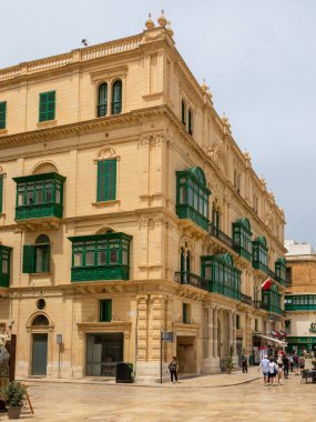 Valletta, Malta 21 Haziran 2021: Şehir merkezinde yeşil ahşap balkonlu geleneksel kireçtaşı bina.