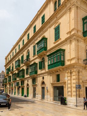 Valletta, Malta 21 Haziran 2021: Şehir merkezinde yeşil ahşap balkonlu geleneksel kireçtaşı bina.