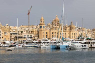 Birgu, Malta 21 Haziran 2021: Tarihi mimari ve kilise kuleleri manzaralı yat ve tekneler limana demir attı.
