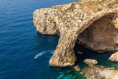 Blue Grotto, Malta 22 Haziran 2021: Turist tekneleri engebeli kireçtaşı kıyılarında geniş bir doğal kemer oluşumuna yaklaşıyorlar.