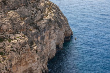 Güneşli bir yaz gününde açık mavi denizli Malta 'daki Blue Grotto' nun sarp kayalıklarının yanındaki renkli tekne..