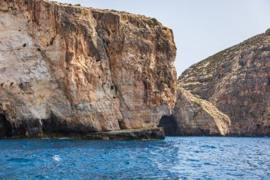 Malta 'daki Blue Grotto sahilindeki dramatik deniz kayalıkları ve doğal mağaralar. Açık gökyüzü ve mavi su.