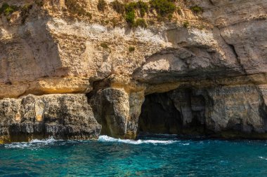 Bir deniz mağarası ve Malta 'daki Blue Grotto' daki sarp kayalıkların yakın görüntüsü. Güneşli bir günde berrak turkuaz su.