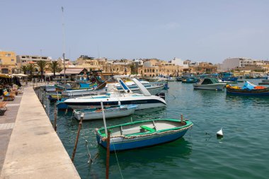 Marsaxlokk, Malta 22 Haziran 2021: Limanda demirlemiş mavi balıkçı teknesi ve arka planda geleneksel Malta tekneleri.