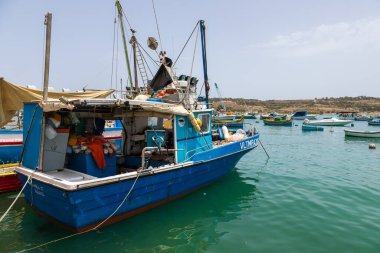 Marsaxlokk, Malta 22 Haziran 2021: Limanda demirlemiş mavi balıkçı teknesi ve arka planda geleneksel Malta tekneleri.