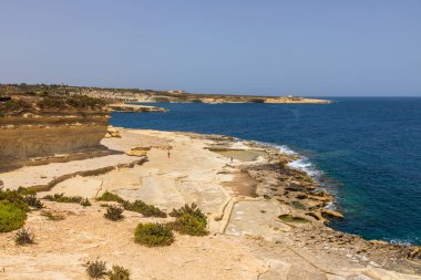 St. Peters Havuzu, Malta 22 Haziran 2021: Güneşli bir günde kayalık kireçtaşı kıyısı ve açık mavi Akdeniz manzarası.