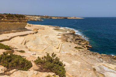 St. Peters Havuzu, Malta 22 Haziran 2021: Güneşli bir günde kayalık kireçtaşı kıyısı ve açık mavi Akdeniz manzarası.