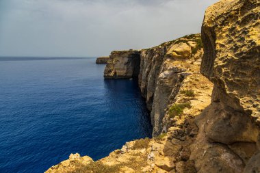 Gozo, Malta 23 Haziran 2021: Akdeniz kıyısındaki yüksek kireçtaşı kayalıklarının yakınındaki küçük tekne.