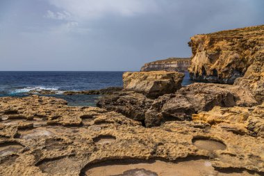 Turkuaz ve koyu mavi Akdeniz sularıyla Gozo Malta 'da Rocky kireçtaşı kıyı şeridi.