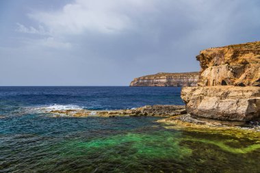Turkuaz ve koyu mavi Akdeniz sularıyla Gozo Malta 'da Rocky kireçtaşı kıyı şeridi.