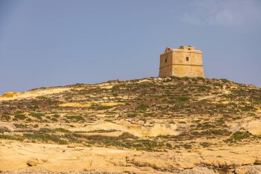 Gozo Malta 'daki sarı kireçtaşı oluşumlarının üzerinde duran antik taş gözetleme kulesi..