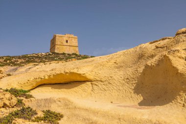 Gozo Malta 'daki sarı kireçtaşı oluşumlarının üzerinde duran antik taş gözetleme kulesi..