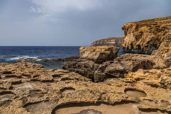 Turkuaz ve koyu mavi Akdeniz sularıyla Gozo Malta 'da Rocky kireçtaşı kıyı şeridi.
