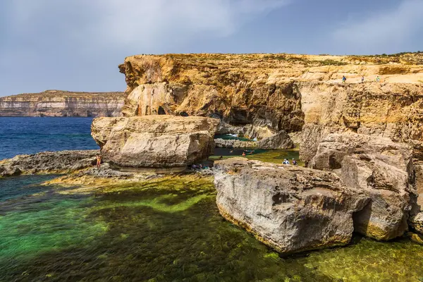 Gozo, Malta 23 Haziran 2021: Turistler Akdeniz 'e bakan engebeli kireçtaşı kayalıklarını keşfediyorlar.