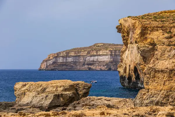 Gozo, Malta 23 Haziran 2021: Turistler Akdeniz 'e bakan engebeli kireçtaşı kayalıklarını keşfediyorlar.