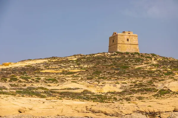 Gozo Malta 'daki sarı kireçtaşı oluşumlarının üzerinde duran antik taş gözetleme kulesi..