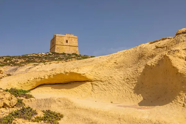 Gozo Malta 'daki sarı kireçtaşı oluşumlarının üzerinde duran antik taş gözetleme kulesi..