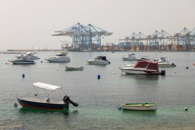 Taht Il-Maqjel, Malta 24 Haziran 2021: Arka planda kireçtaşı kemer ve engebeli kıyı şeridi bulunan turkuaz sulara demirlenmiş yatların yayın manzarası.