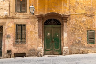 Valletta, Malta 26 Haziran 2021: Valletta, Malta 'da geleneksel Malta balkonlarının yer aldığı arabalar ve tarihi evlerle dolu dar bir cadde.