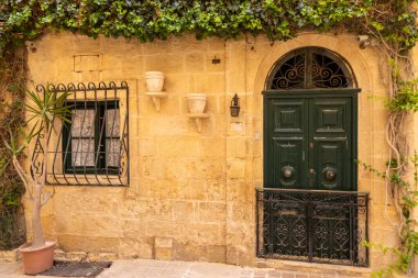 Valletta, Malta 26 Haziran 2021: Valletta, Malta 'da geleneksel Malta balkonlarının yer aldığı arabalar ve tarihi evlerle dolu dar bir cadde.