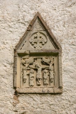Saaremaa, Estonya 24 Ağustos 2021: Tarihi bir kilisenin duvarında çarmıha gerilme sahnesini tasvir eden bir ortaçağ taşı kabartması.