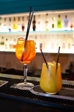 Turuncu ve buzlu taze kokteyller. Barda alkollü, alkolsüz bir içecek var. Gece kulübünde portakallı bir bardak portakal kokteyli. Bir bardak kokteyl, arka planda bar..