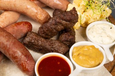 Soslu kızarmış sosisler, yakın plan, soslu. Geleneksel Alman mutfağı, sucuk ve ketçap. Sosis bbq yemek için hazır. Farklı soslu kızarmış sosis..