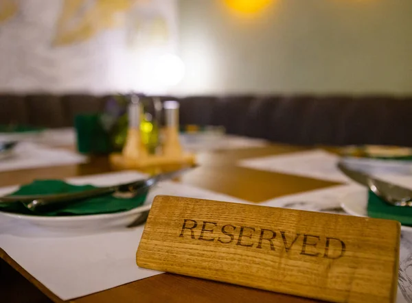 Sign Reserved on a table in restaurant. Wooden sign reserved on a table in cafe. Reserved table in restaurant for guests. Reservation in restaurant.