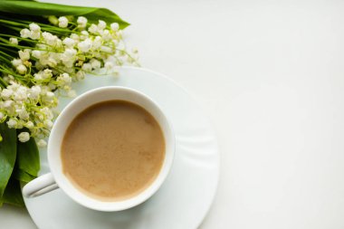 Kahve fincanı ve bir buket çiçekli vadi zambağı. Yukarıdan görünüm, sabah konsepti, metin için boşluk kopyala.