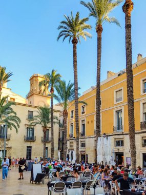 ALICANTE, SPAIN - JUNE 3, 2023: Calle Mayor square in Alicante with its palm trees and outdoor cafe. Spanish architecture and palm, touristic place, downtown, vacation concept. clipart