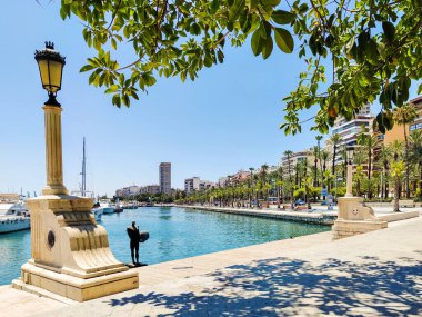 ALICANTE, İSPAN - 5 Temmuz 2023 Puerta del Mar Square Fountain ve Meli Alicante Hotel. Alicante 'nin şehir merkezinde ünlü bir yer. Palmiyeler, arabalar ve İspanya bayrağı.