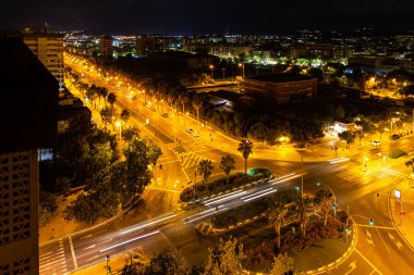Alicante, İspanya 'daki hava manzaralı cadde, gece vakti. Palmiye ağaçları ve arabalarla dolu bir yol, gece fotoğrafları. Şehir manzarası, ışıklar, modern binalar..