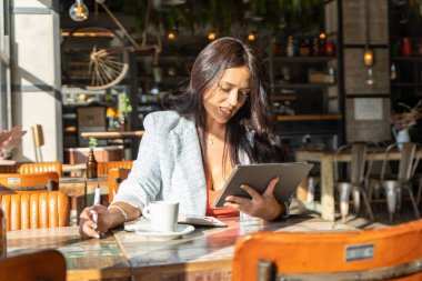 Bir kafede çalışırken dijital tablet kullanan bir kadın. Teknoloji ve iş konsepti.
