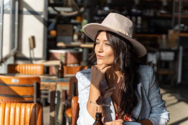 Bir kafede rahatlarken pencereden dışarı bakan bir kadın..