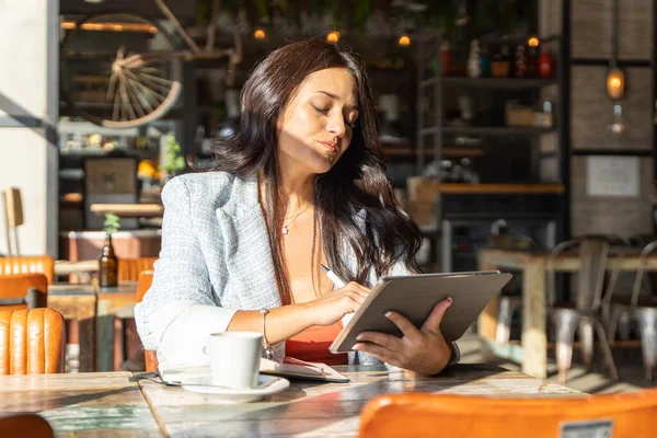Kafede otururken dijital tablete şaşkın şaşkın bakan bir kadın. Teknoloji konsepti.